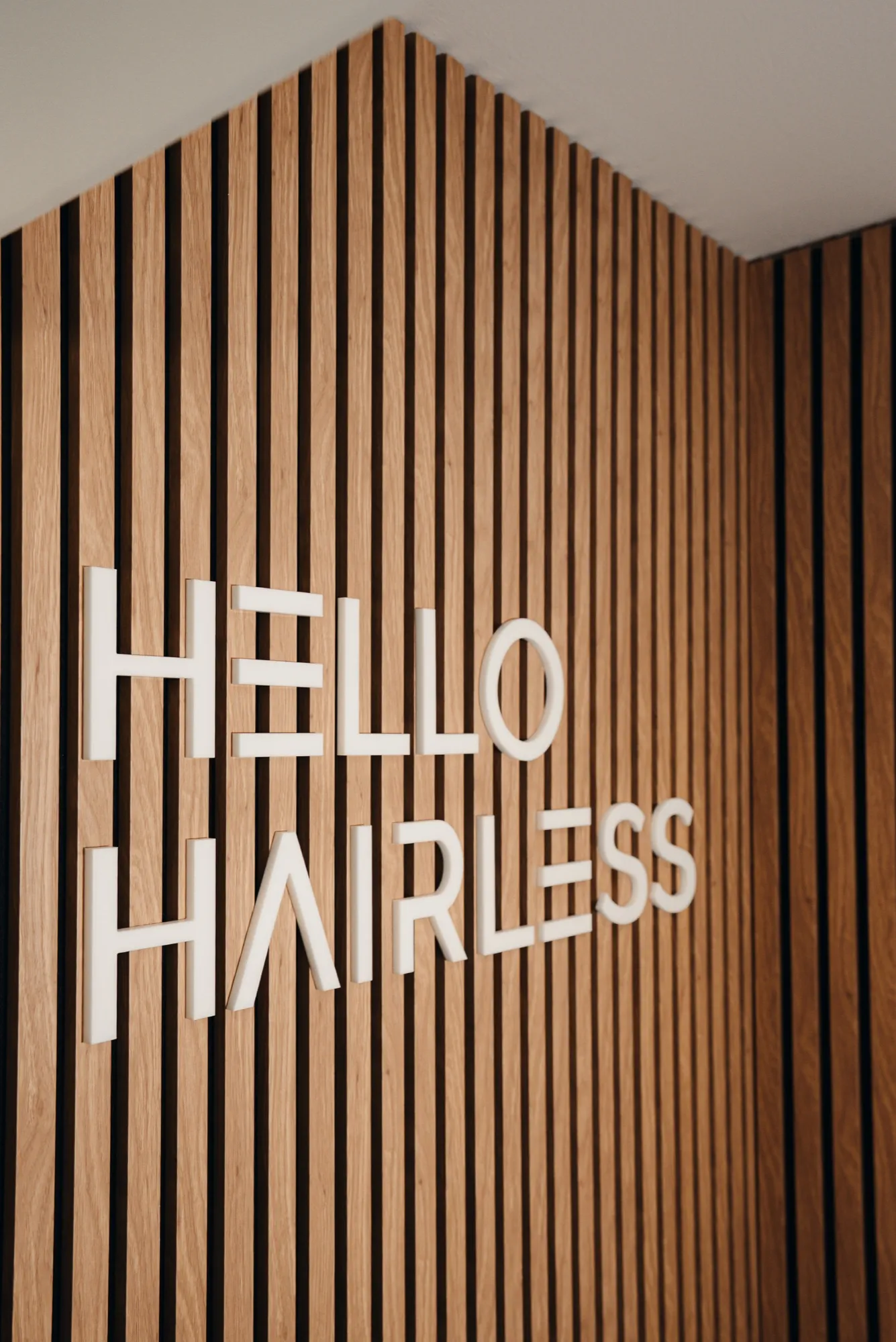 HelloHairless Logo an der Wand im Studio München